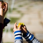 a woman holding a child's hand with a flower in it