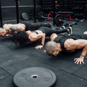 Fitness enthusiasts performing push-ups in a Mexico City gym. Emphasizing teamwork and strength.